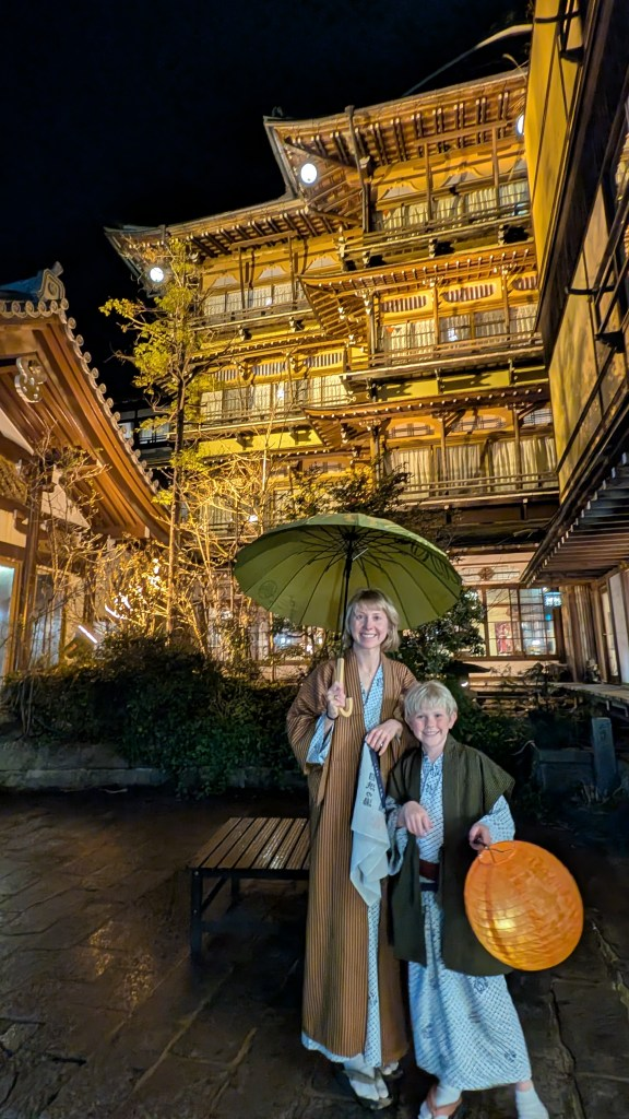 Family in yukata robes walking lantern-lit cobblestone streets of Shibu Onsen